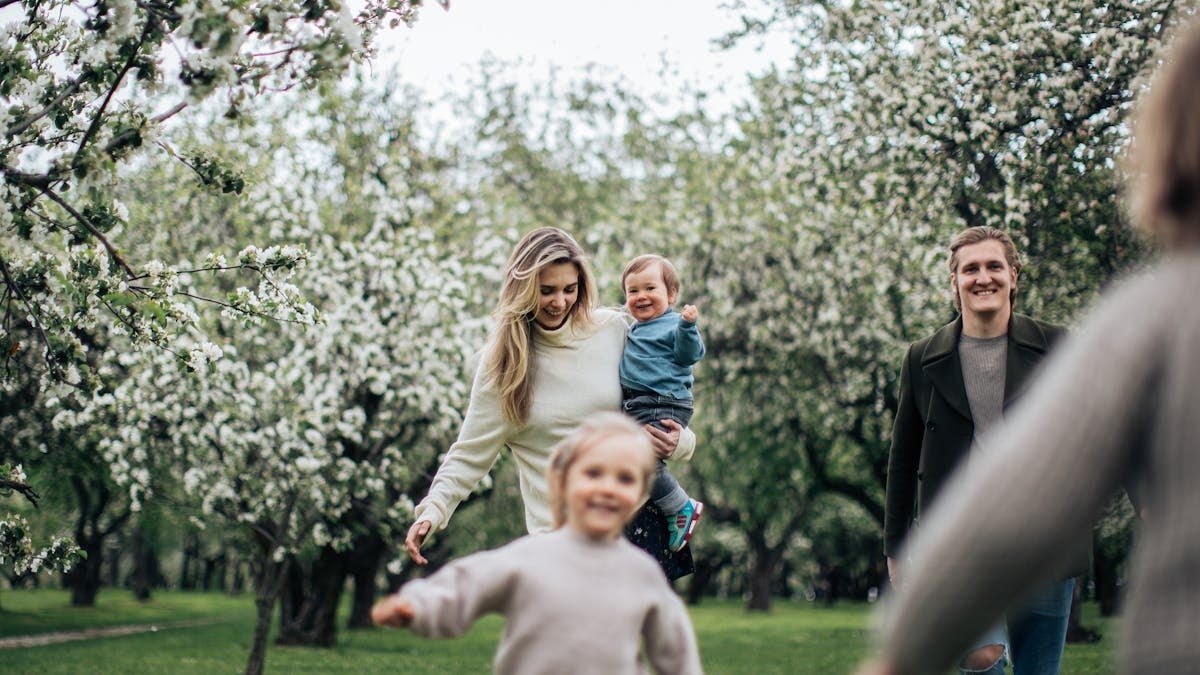 A joyful family enjoys a playful day outdoors amidst blossoming trees in spring.